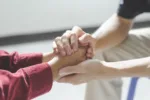 Close-up of man psychologist or psychiatrist sitting and holding hands palm of his woman patient for encouragement. PTSD Mental health concept,